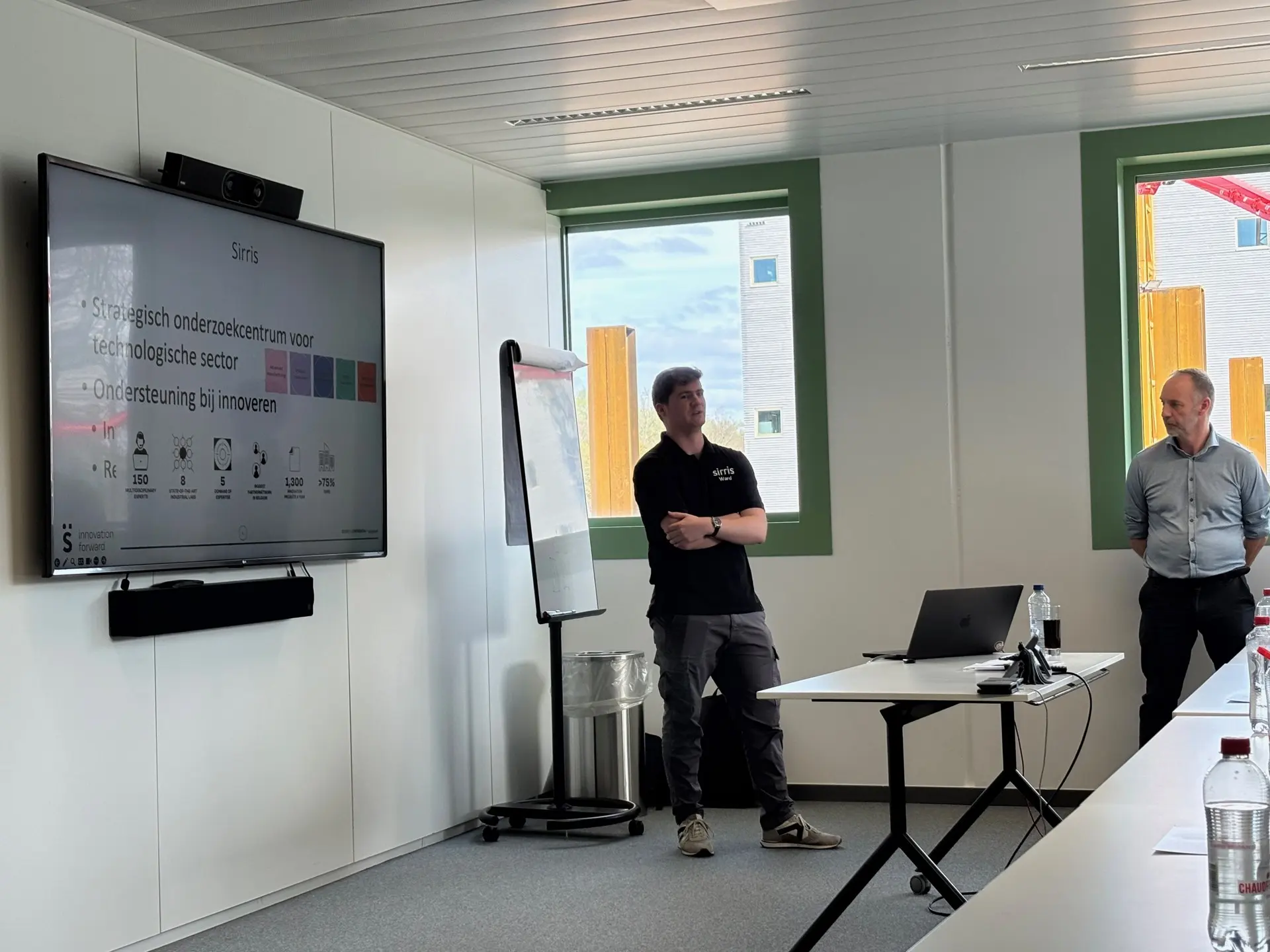 Twee sprekers bij het scherm tijdens de voorstelling van Sirris